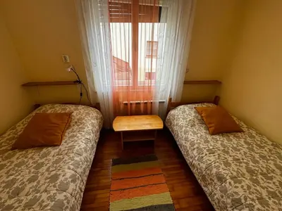 two beds in a room with a table and a window at Rooms Apartma Cerknica in Cerknica