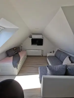 a attic living room with two couches and a tv at Apartments Bernard in Bled