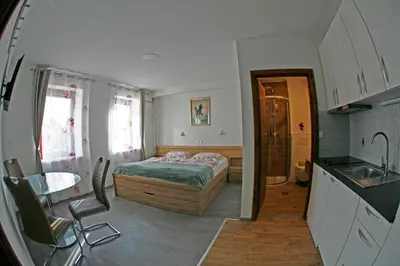 a bedroom with a bed and a table and a kitchen at Apartments Bernard in Bled