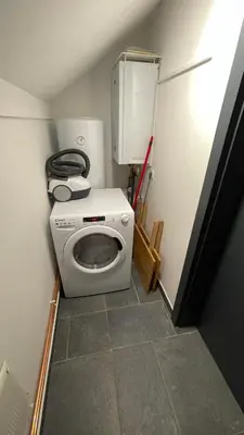 a laundry room with a washing machine and a refrigerator at Apartma Zala, Golte in Mozirska Koča