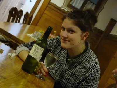 a young man sitting at a table with a bottle of wine at Farm Stay Frank Ozmec Wine and Glamping estate in Ljutomer