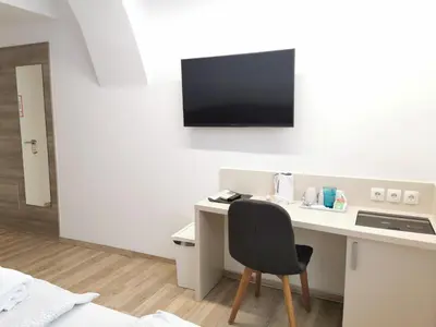a desk with a chair and a television on a wall at Rooms Ambrožič in Ljubljana