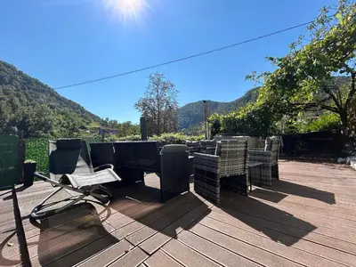 a table and chairs on a deck with mountains in the background at 22 - The Old Workshop with fired wood hot tub in Tolmin