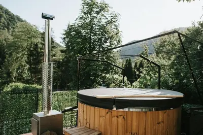 a jacuzzi tub in a garden with a fence at 22 - The Old Workshop with fired wood hot tub in Tolmin