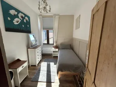 a small bedroom with a bed and a window at 22 - The Old Workshop with fired wood hot tub in Tolmin