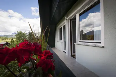a balcony with red flowers and a window at Home with views on Alps in Bohinj
