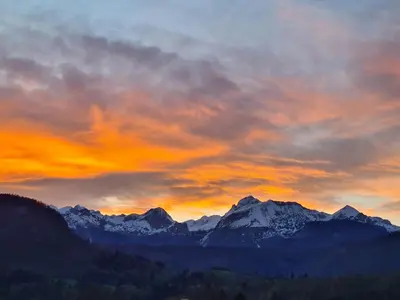 a sunset over a mountain range with snow covered mountains at Home with views on Alps in Bohinj