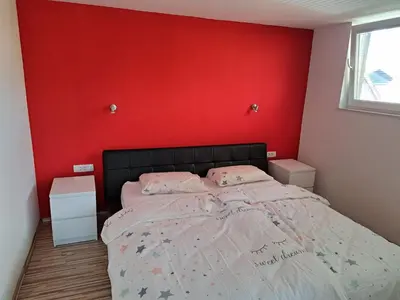 a bedroom with a bed with a red wall at Apartma Jaka in Ljubljana