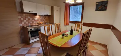 a kitchen with a wooden table with chairs and a bottle of wine at Apartments Oman in Kranjska Gora