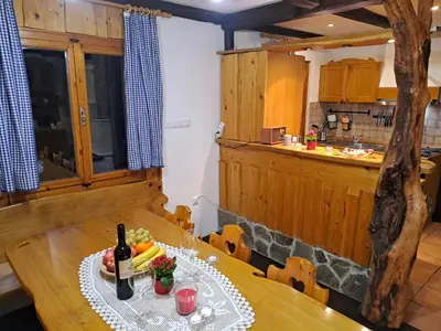 a dining room with a table with a bottle of wine at Bohinj, Metka - vacation house Pri Metki in Bohinj