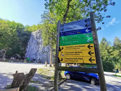 a sign with arrows on it next to a car at Bohinj, Metka - vacation house Pri Metki in Bohinj