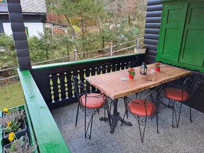 a wooden table and chairs on a balcony with a green door at Bohinj, Metka - vacation house Pri Metki in Bohinj