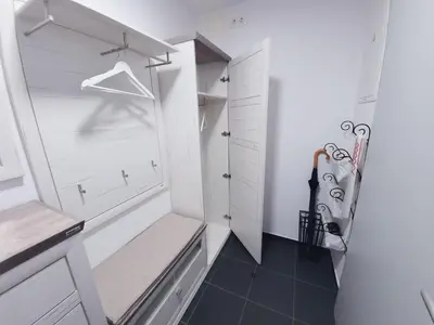 a walk in closet with white cabinets and a bench at Apartma M&J in Mojstrana
