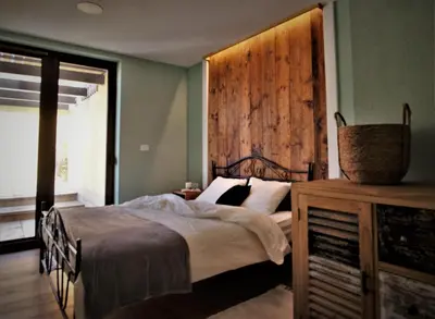 a bedroom with a bed and a wooden wall at Olivea in Dobrovo