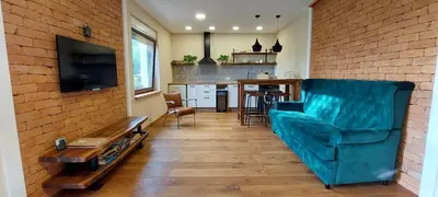 a living room with a blue couch and a kitchen at Olivea in Dobrovo