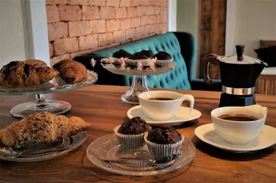 a table with plates of muffins and cups of coffee at Olivea in Dobrovo