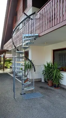 a spiral staircase in front of a building with plants at Draga - 2 bedroom apartment in Tržič