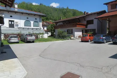 a parking lot in front of a house with cars parked at Apartments Masera in Kobarid