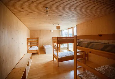 a room with three bunk beds and a table at Youth Hostel Punkl in Ravne na Koroškem