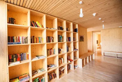 a library with wooden shelves filled with books at Youth Hostel Punkl in Ravne na Koroškem