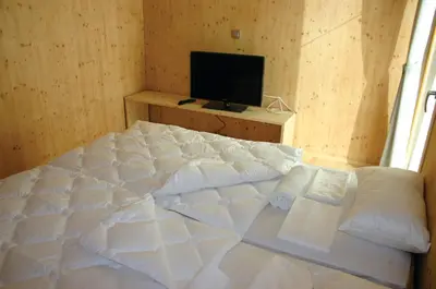 a bedroom with a large bed and a television at Youth Hostel Punkl in Ravne na Koroškem