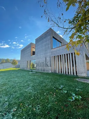 an external view of a building with a grass field at Youth Hostel Punkl in Ravne na Koroškem