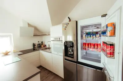 a stainless steel refrigerator in a kitchen with white cabinets at Sunny Oak Estate in Mengeš