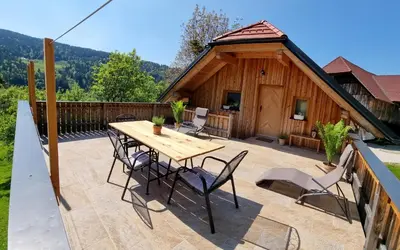 a patio with a wooden table and chairs in front of a cabin at Apartma1 pri Adamu in Mislinja