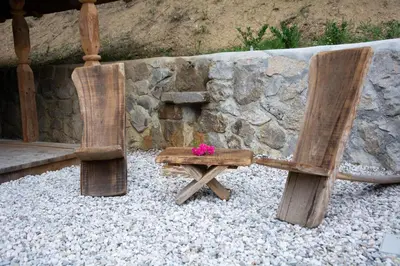 two wooden chairs sitting next to a stone wall at Apartma kašča in Domžale