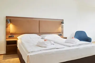a bedroom with a large bed and a blue chair at Thermal Resort Hotel Lendava in Lendava