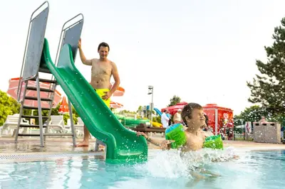 two young men playing on a slide in a swimming pool at Thermal Resort Hotel Lendava in Lendava