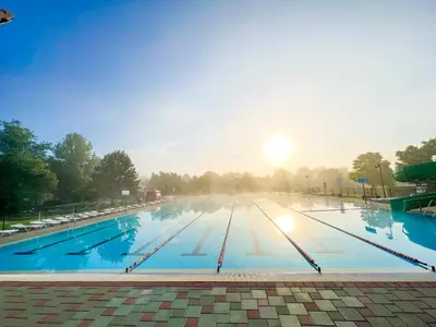 a large swimming pool with the sun in the background at Thermal Apartments Lendava in Lendava
