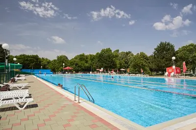 a large swimming pool with people sitting around it at Thermal Apartments Lendava in Lendava