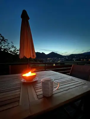 a candle and a cup on a table with an umbrella at Mountain Vista Apartment in Bled