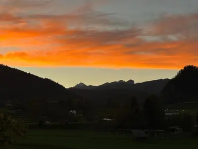 a sunset over a field with mountains in the background at Mountain Vista Apartment in Bled