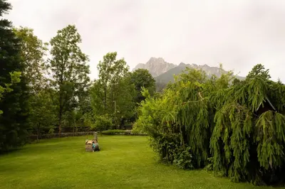 a group of people sitting in a grass field at JM Alpine Apartments in Kranjska Gora