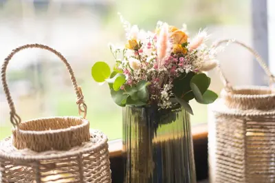 a vase of flowers in a window with two baskets at JM Alpine Apartments in Kranjska Gora