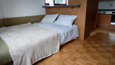 a bed with white sheets in a room with wooden floors at Apartma Alda in Preserje
