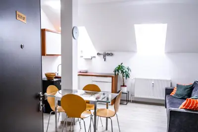 a dining room and kitchen with a glass table and chairs at The City Loft in Ljubljana