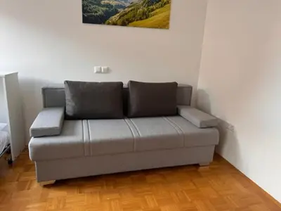 a couch in a living room with a painting on the wall at Studio Mavrinc in Kranjska Gora