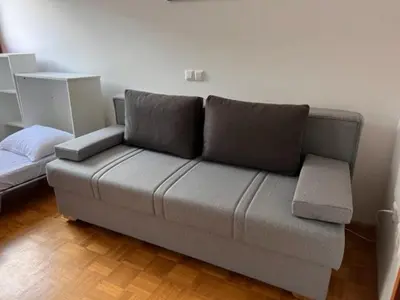 a gray couch in a room with a bed at Studio Mavrinc in Kranjska Gora