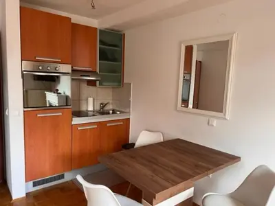 a kitchen with a wooden table and white chairs at Studio Mavrinc in Kranjska Gora