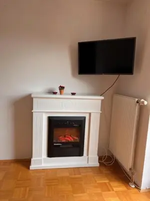 a living room with a fireplace with a tv on the wall at Studio Mavrinc in Kranjska Gora