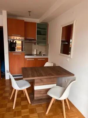 a kitchen with a wooden table and two white chairs at Studio Mavrinc in Kranjska Gora