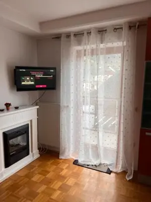 a living room with a window with a television and a fireplace at Studio Mavrinc in Kranjska Gora
