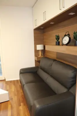 a black leather couch in a living room with a clock at Studio apartma Terme Ptuj in Ptuj