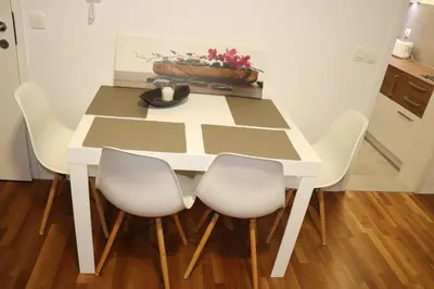 a white table with white chairs and a bowl of flowers at Studio apartma Terme Ptuj in Ptuj