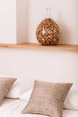 a pillow on a bed with a vase on a shelf at Vina Kobal, Kobal Family Estate in Štanjel