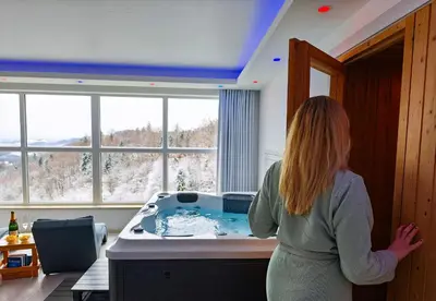 a woman standing in a kitchen with a hot tub at Private wellness with panoramic view, sauna & jacuzzi in Maribor