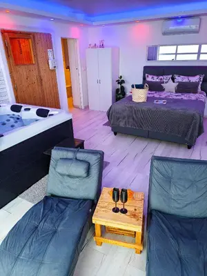 a bedroom with two beds and a tub and two chairs at Private wellness with panoramic view, sauna & jacuzzi in Maribor
